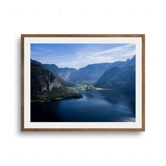 Plakat z fotografią przedstawiającą panoramiczny widok na jezioro Hallstatt w Austrii, otoczone przez majestatyczne Alpy.